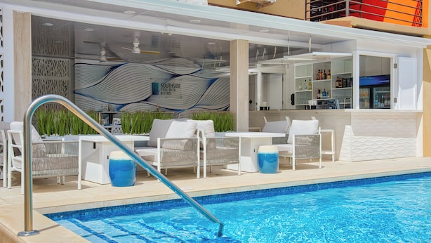 A poolside area with lounge chairs, a bar, and a pool.
