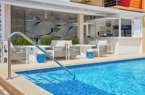 A poolside area with lounge chairs, a bar, and a pool. - Melbourne Inn (St. Lawrence Gap)