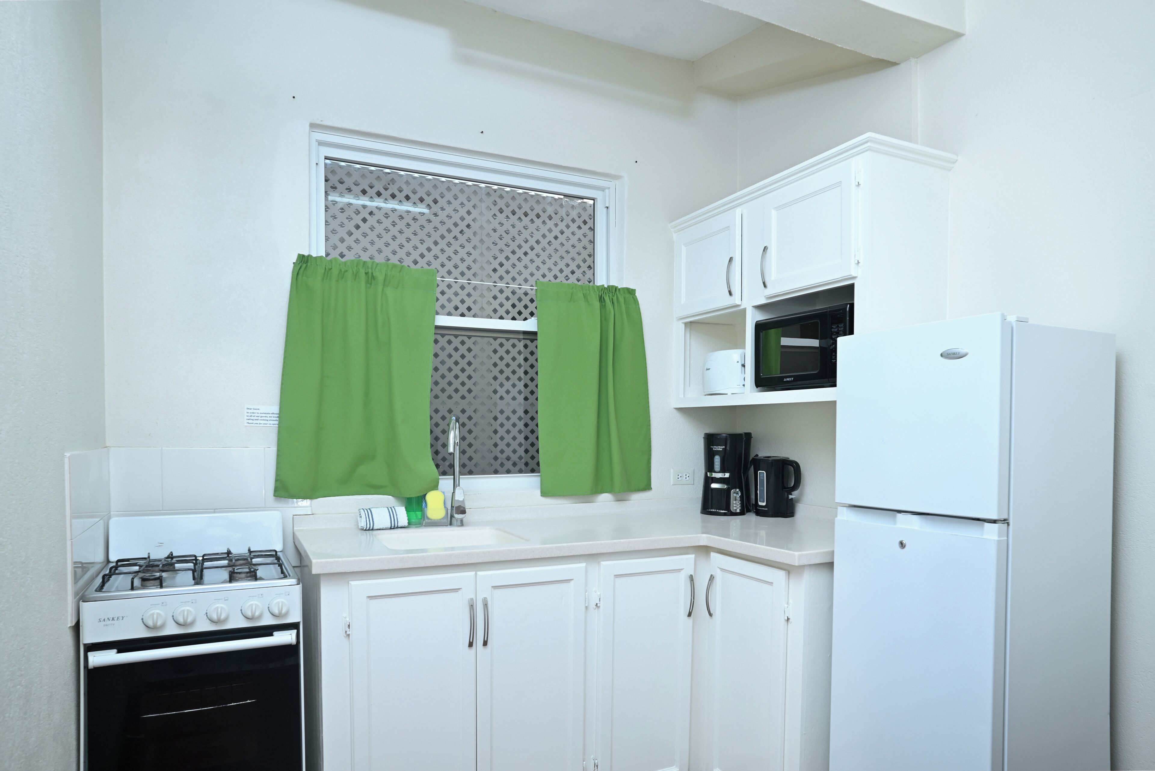 A compact kitchen with white cabinets, a gas stove, a microwave, and a refrigerator.