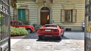 A red sports car parked in front of a building with a stone-paved entrance and a metal gate. - Residence Michelangiolo (Florence)
