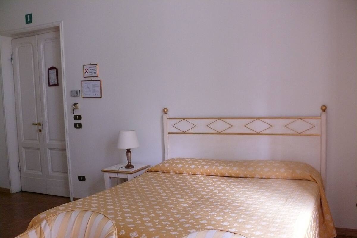 Ein Hotelzimmer mit einem Bett, einem Nachttisch, einer Lampe und einem Sessel.