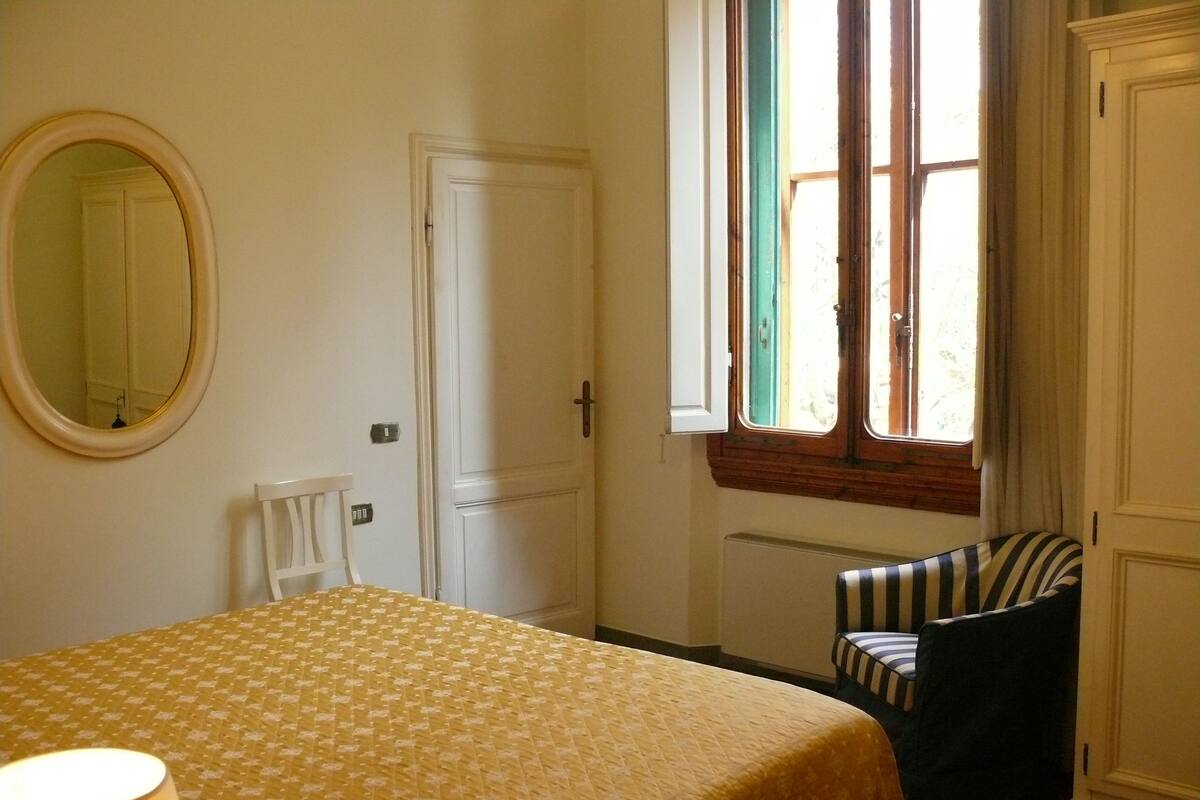 Ein Schlafzimmer mit Bett, Stuhl, Fenster und Heizkörper.