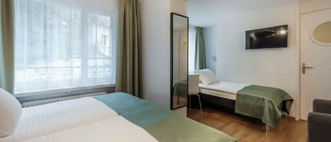 A hotel room with two beds, a television, a mirror, and a window with curtains.