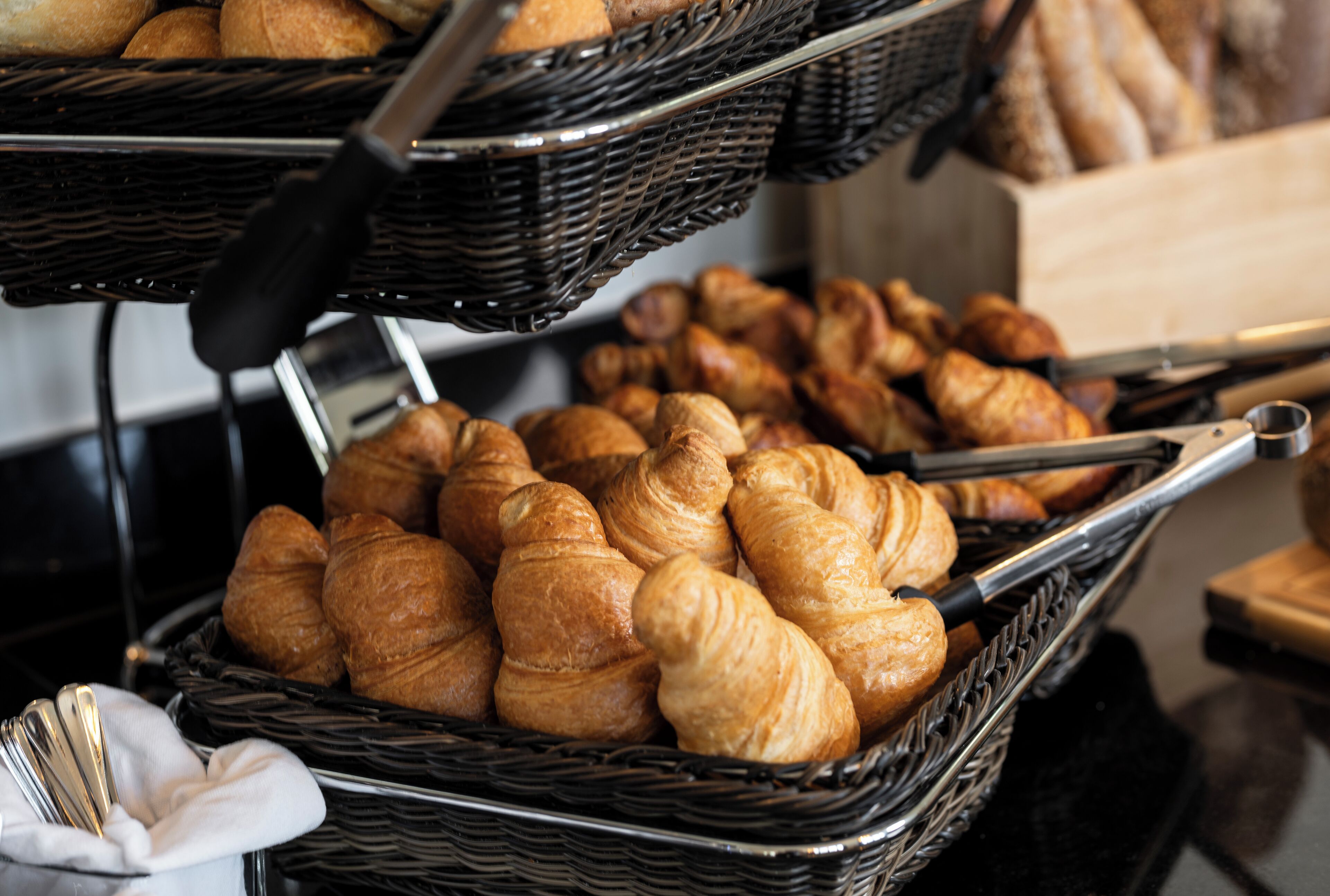 Une variété de produits de boulangerie, notamment des croissants et du pain, présentés dans des paniers en osier.