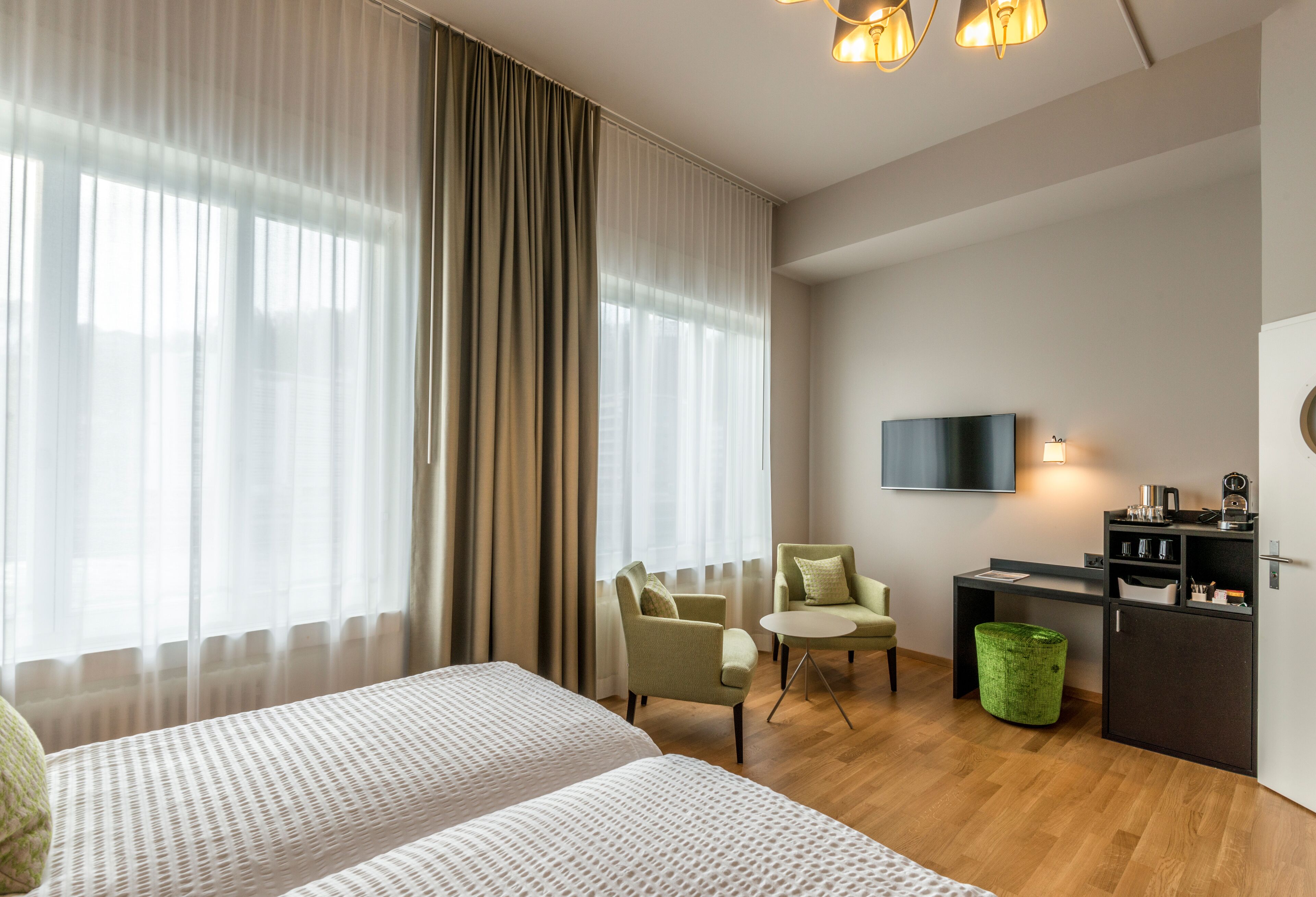 Ein Hotelzimmer mit zwei Betten, einem Schreibtisch, einem Stuhl, einem Fernseher und einem Mülleimer.