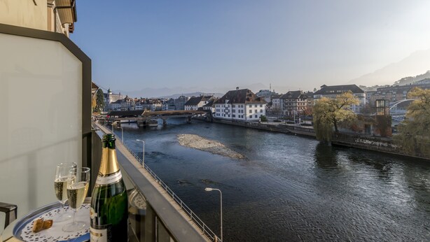 A balcony with a view of a river, buildings, and a bridge.