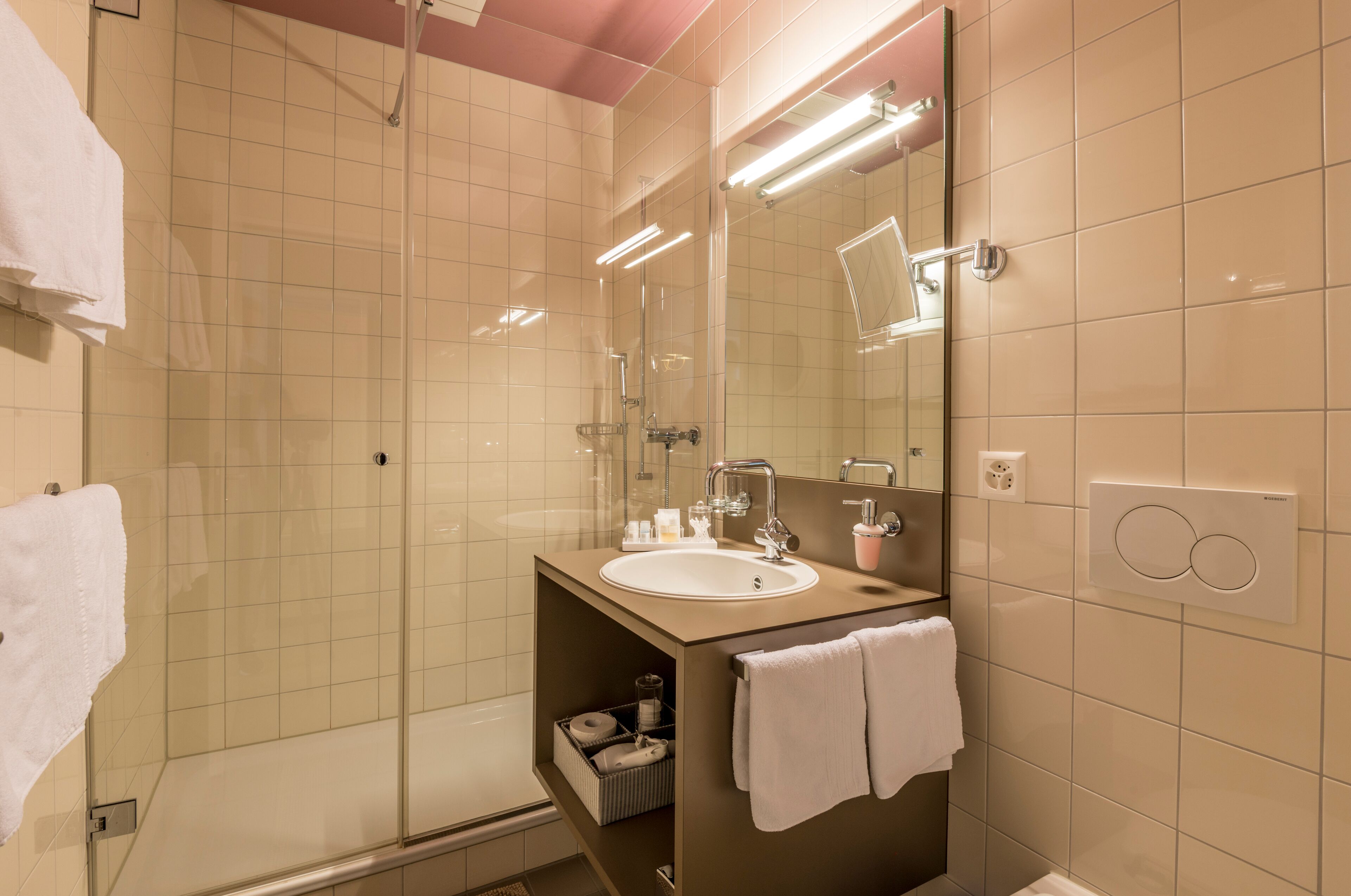 Un baño moderno con cabina de ducha de vidrio, un lavamanos con espejo y un perchero para toallas.