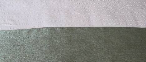 Una cama con ropa de cama blanca y un edredón verde.