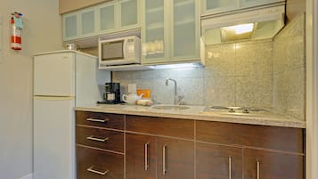 A compact kitchen with a refrigerator, microwave, and stove.