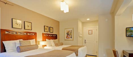 A hotel room with two beds, a desk, and a chair.