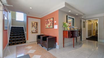A hotel lobby with a staircase, a sofa, a console table, and a painting on the wall.