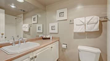 A bathroom with a sink, mirror, towel rack, toilet, and framed pictures on the wall.