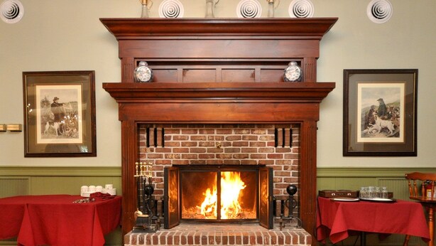 A fireplace with a brick surround and a wooden mantel, flanked by framed pictures.