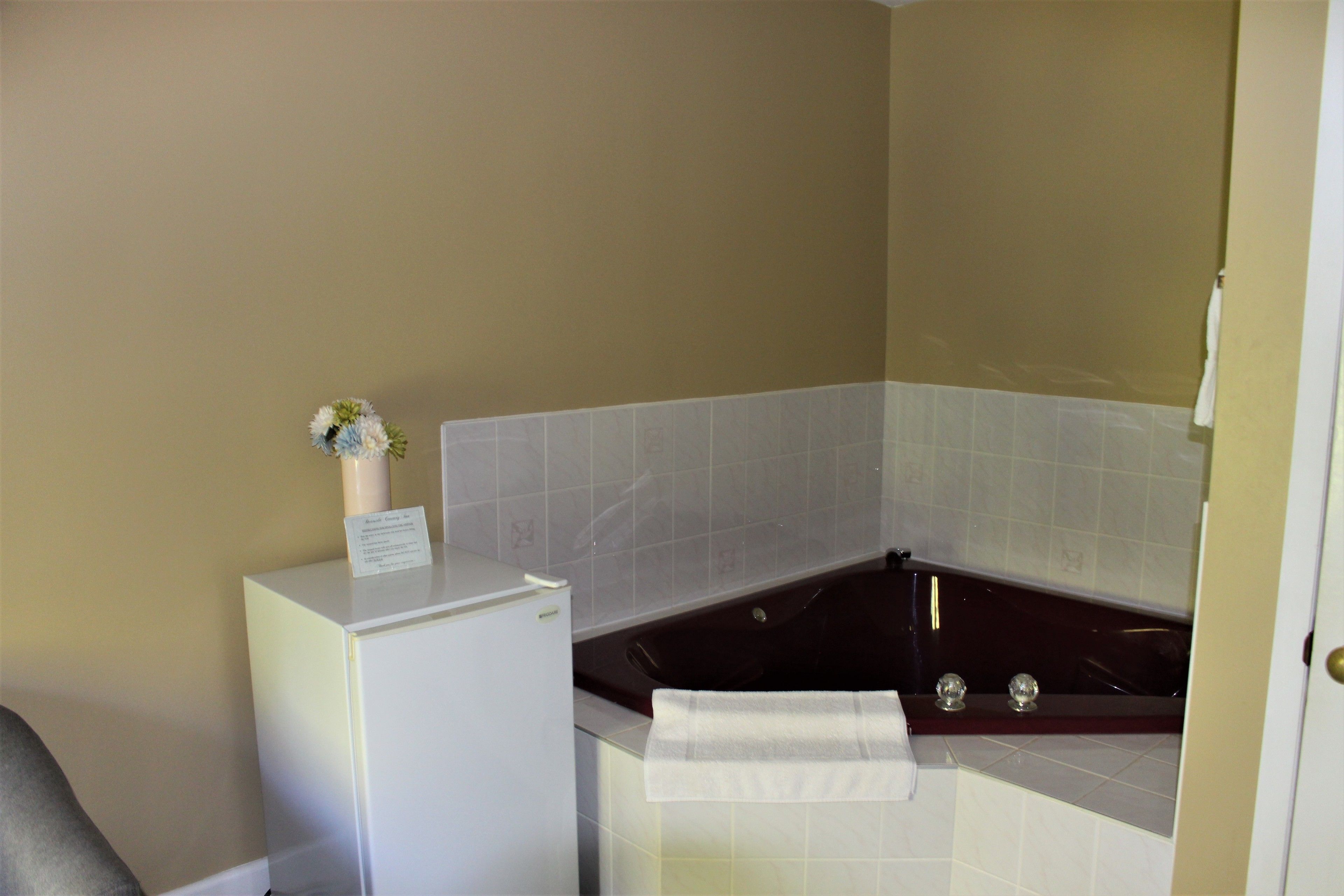 A bathroom with a bathtub, a white sink, and a small refrigerator.