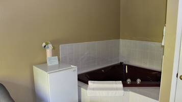 A bathroom with a bathtub, a white sink, and a small refrigerator.