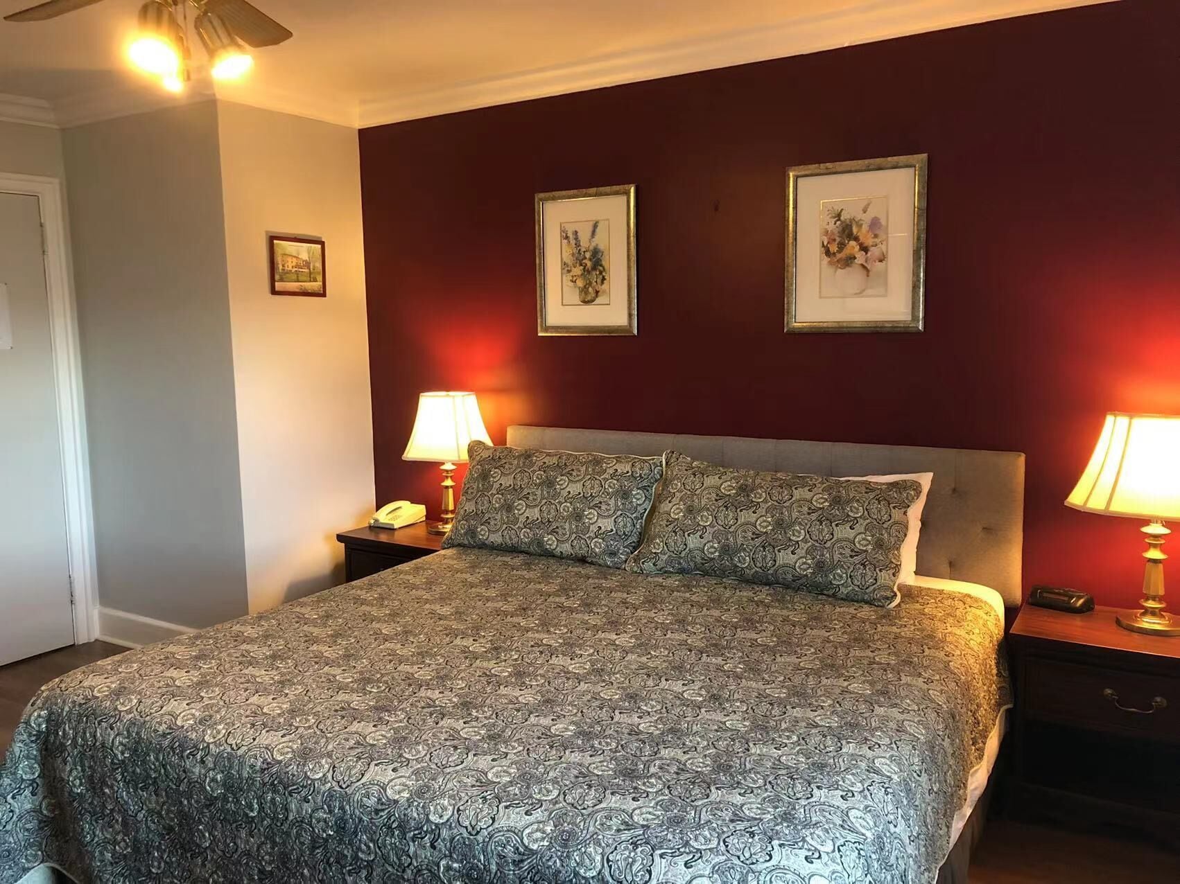 A neatly made bed with patterned bedding, two bedside lamps, and framed artwork on the wall.
