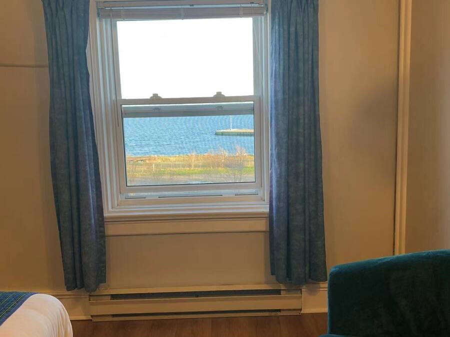 Una habitación con ventana que da a una masa de agua, una cama y una silla.
