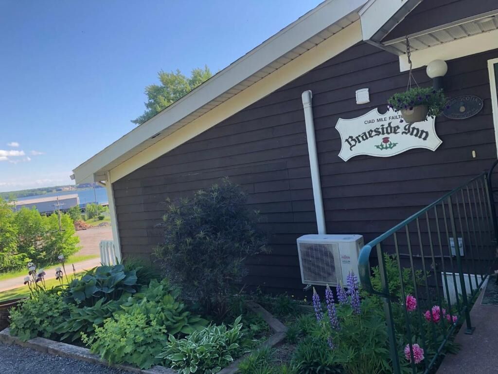 A building with a sign that reads "Braeste Inn" and a small garden with various plants and flowers.