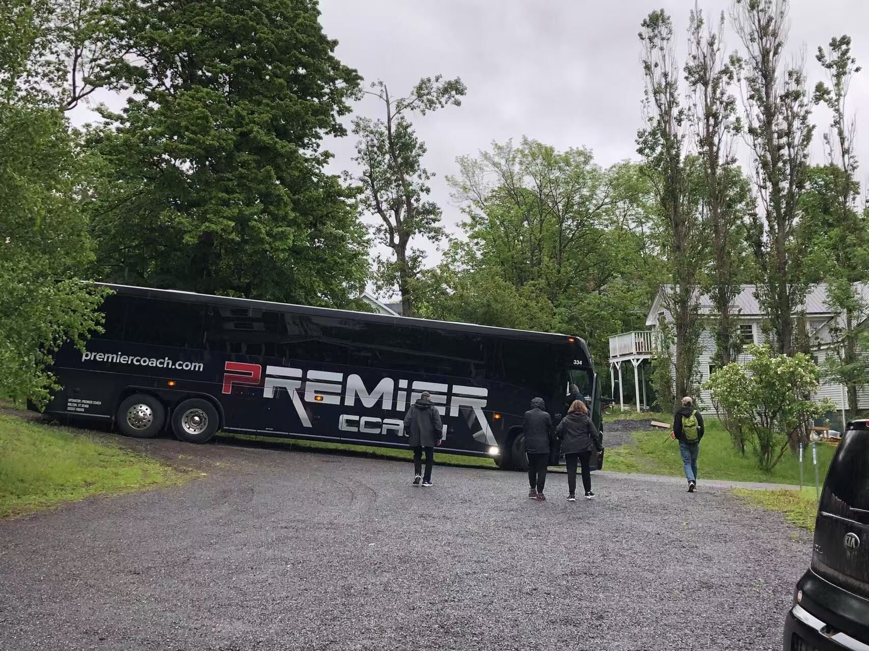 A black bus with "premier coach" branding parked on a gravel road.