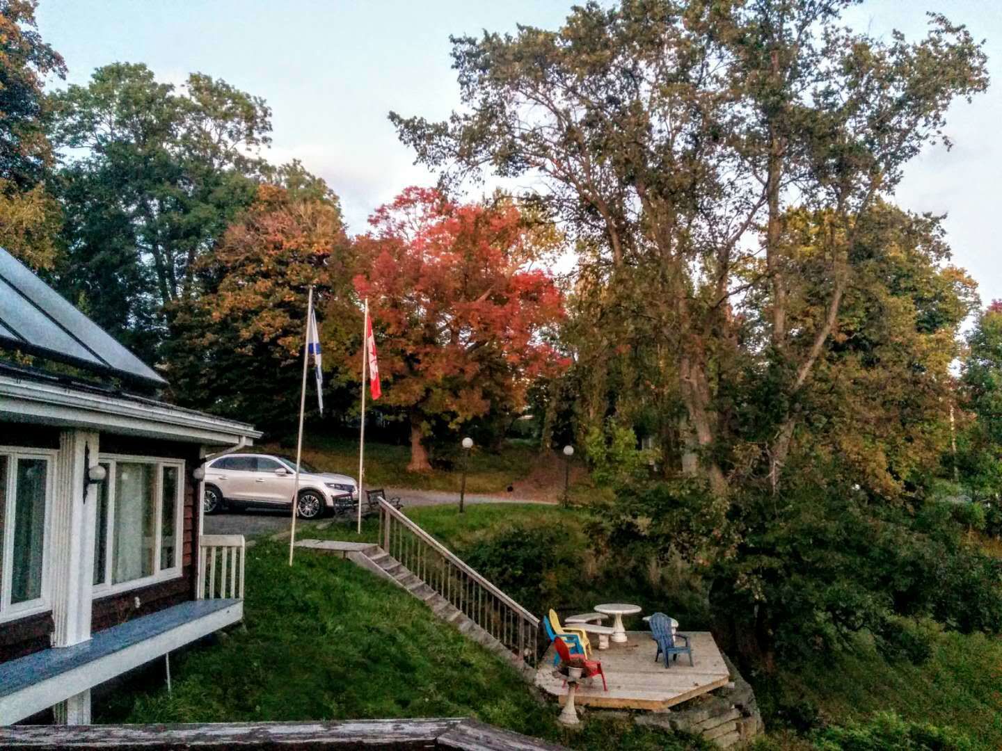 A house with a porch, a car parked in the driveway, and a deck with outdoor furniture.