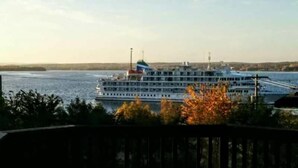A large cruise ship docked at a port with a view of the water and distant land.
