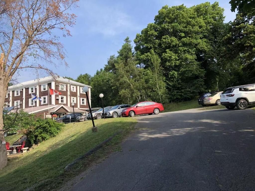 Un estacionamiento con un edificio al fondo, un auto rojo y un SUV blanco.