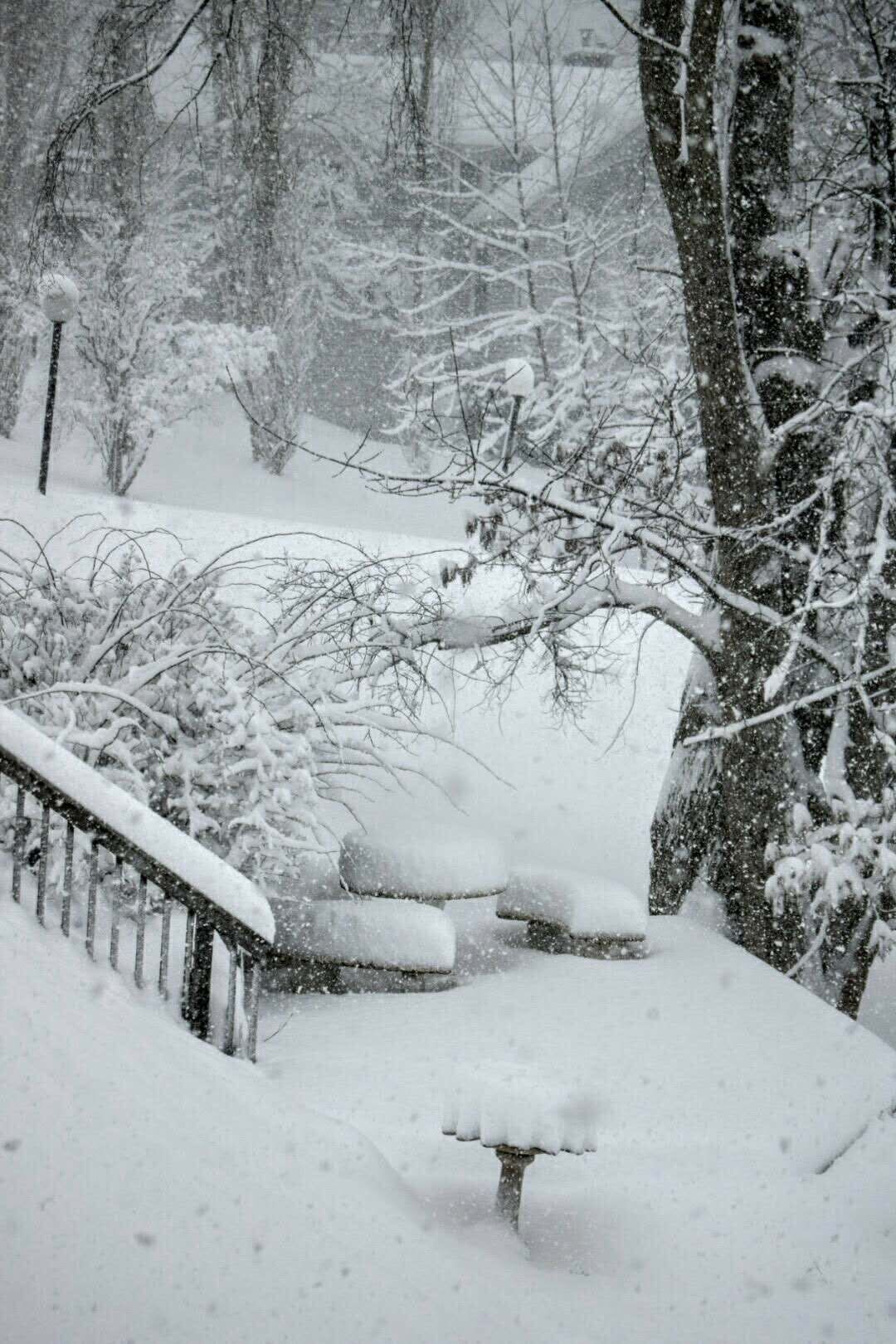 Ett snötäckt utomhusområde med en bänk och ett räcke.