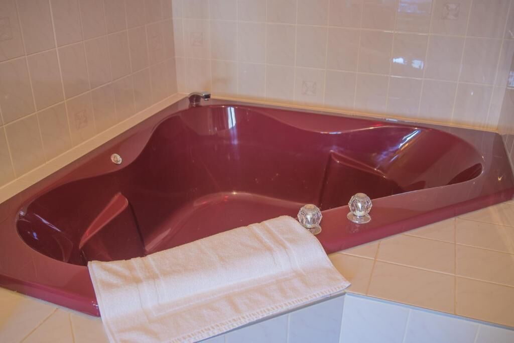 Une baignoire rouge avec une serviette blanche.