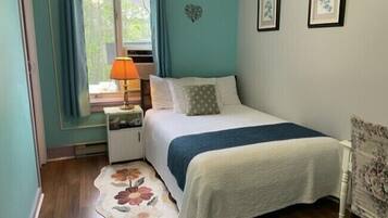 Une chambre à coucher comprenant un lit, une table de chevet, une lampe, un tapis à motifs floraux et deux tableaux encadrés accrochés au mur.