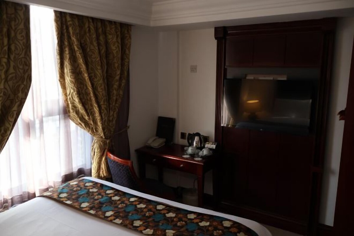 A hotel room with a bed, a desk, a telephone, and a minibar.