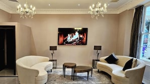 Una sala de estar con dos sofás, una mesa de centro y un televisor que muestra una chimenea.