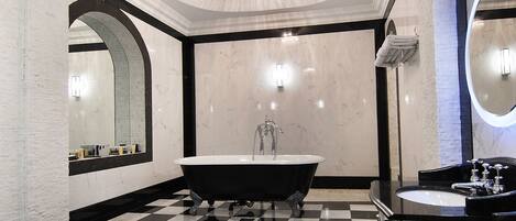 A bathroom with a black and white checkered floor, a freestanding bathtub, a large mirror, and a modern sink.