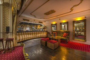 Eine Bar mit einer gebogenen Theke, einer Couch mit roten Kissen und einem Spiegel an der Wand.