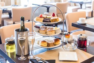 Ein dreistöckiges Dessertregal mit verschiedenen Backwaren und einer Champagnerflasche auf einem Tisch in einem Restaurant.