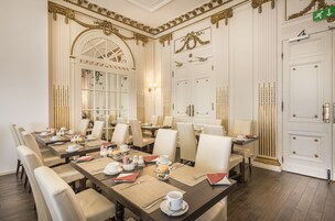 Un comedor formal con varias mesas dispuestas para comidas, sillas elegantes y decoración clásica.
