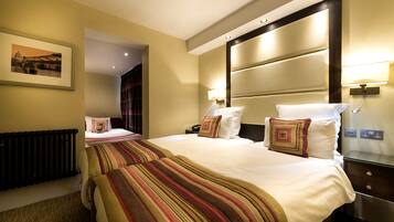 A hotel room with a large bed, a bedside table with a lamp, a framed picture on the wall, and a radiator.