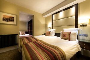 Ein Hotelzimmer mit einem großen Bett, einem Nachttisch mit Lampe, einem gerahmten Bild an der Wand und einer Heizung.