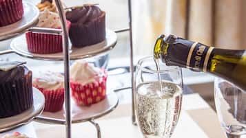 A tiered stand with cupcakes and a bottle of champagne being poured into a glass.