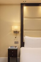 Ein Hotelzimmer mit einem Bett, einem Nachttisch mit Lampe und einer Steckdose.