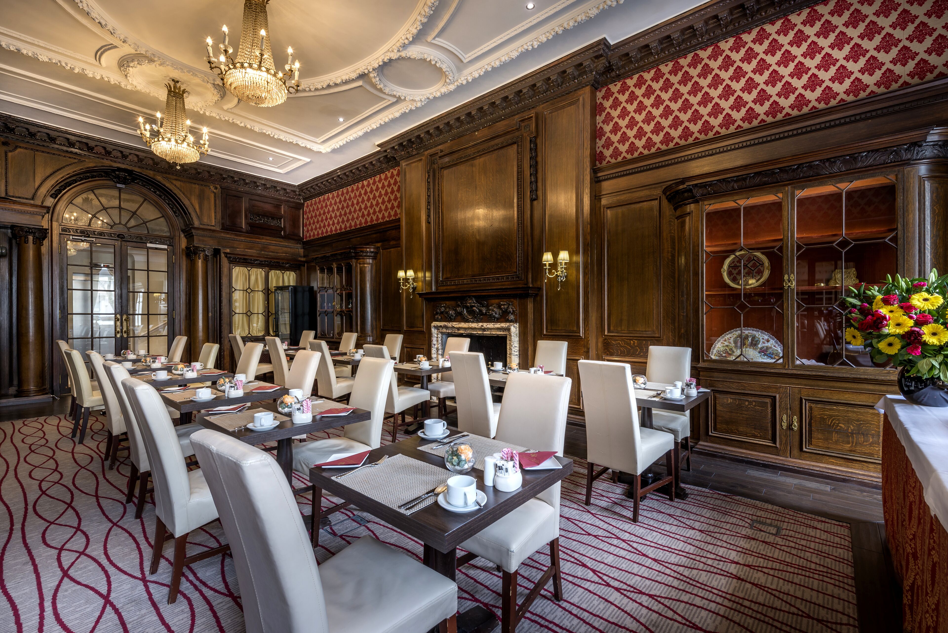 Un comedor formal con varias mesas y sillas, chimenea y paneles decorativos en las paredes.