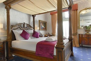 Un letto a baldacchino con tenda, un comodino, una cassettiera e un quadro appeso al muro.