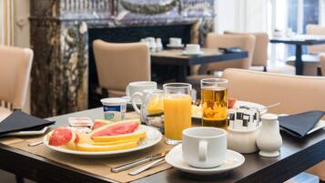 Una mesa de desayuno con una porción de sandía, rodajas de naranja y una taza de café.