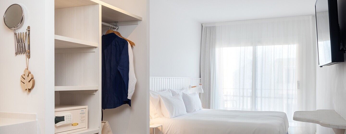 A bedroom with a bed, a wardrobe, a mirror, and a television.