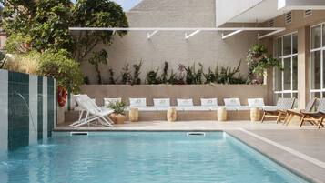 Una piscina al aire libre, sillones reclinables de piscina
