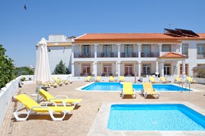 Una piscina al aire libre, sillones reclinables de piscina