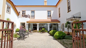 A courtyard with a cobblestone path, a bench, and a reception area. - Lam Hotel Convento d'Alter (Alter do Chao)