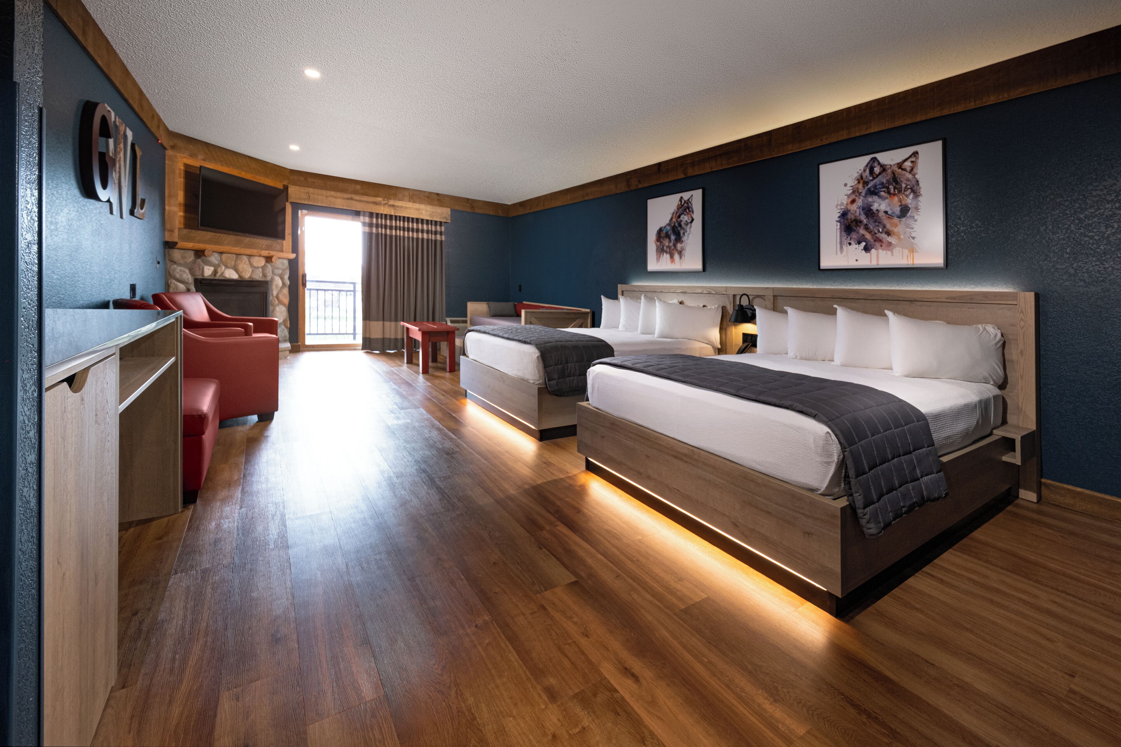 A hotel room with two beds, a TV, a fireplace, and artwork on the walls.