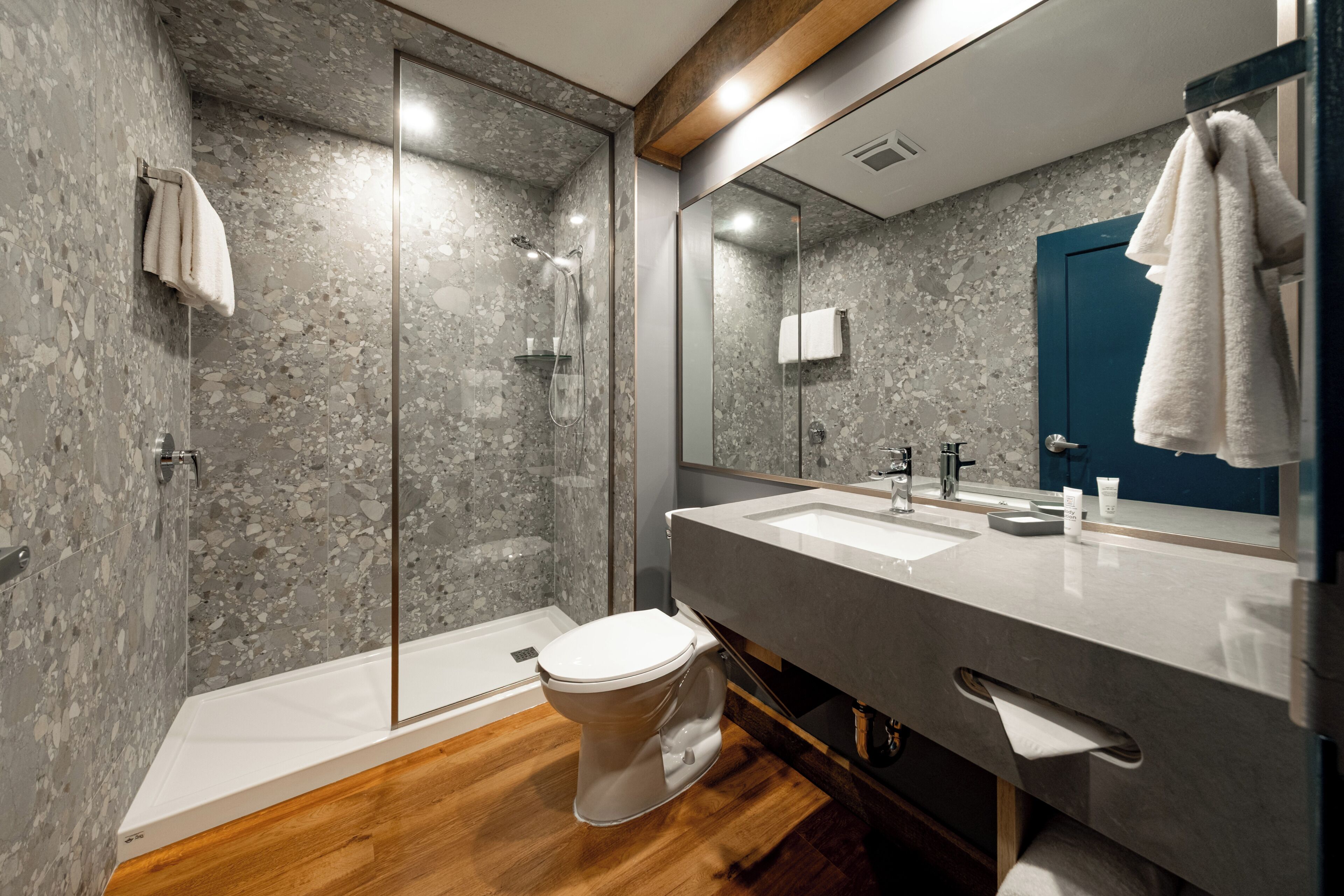 A modern bathroom with a shower, toilet, and sink.