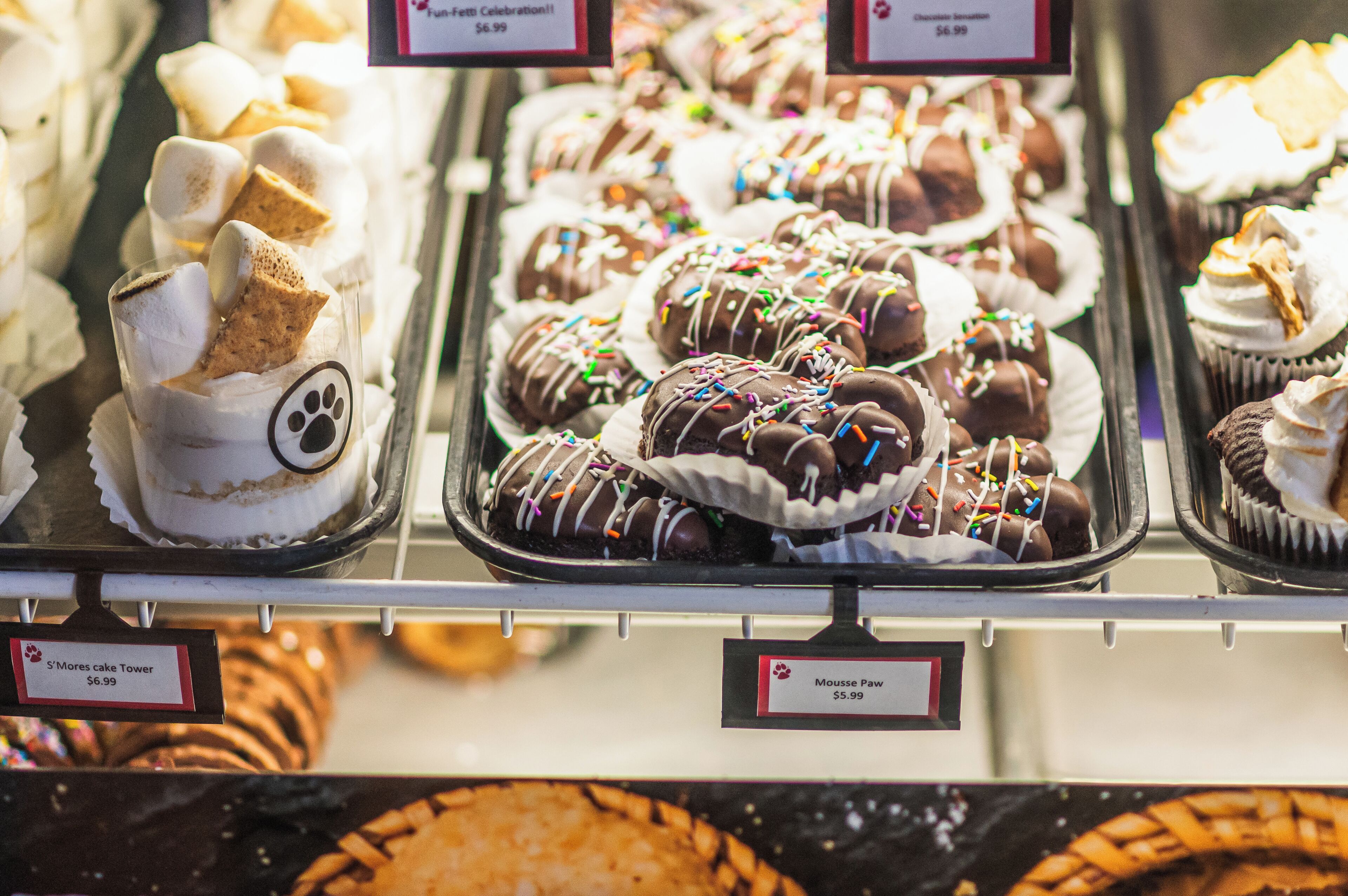 Een bakkerijdisplay met verschillende gebakjes en desserts, waaronder een taarttoren en chocolade lekkernijen.