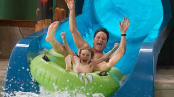 A water slide with a person and a child on an inflatable tube.